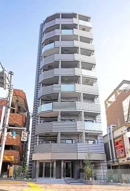 都市部に位置するモダンな多階建てアパートメントビルの外観、曲線的デザインのバルコニー、明るい日差し