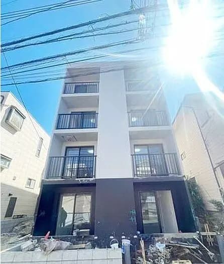 日差しが輝く新築のモダンなマンション外観、電線が多い都市風景