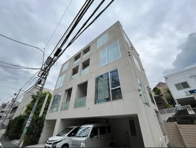 現代的なデザインの都市型アパート外観、駐車スペース付き、電線と曇り空