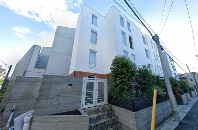 - モダンなデザインの多棟住宅、白い外壁と庭に囲まれたエントランス、緑豊かな植栽が施された外観
