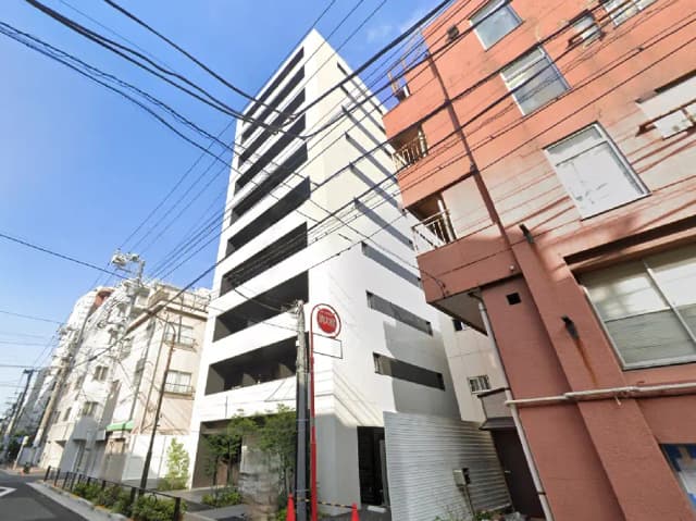 - モダンなデザインのマンションの外観、周囲の住宅や電柱が見える都市の風景