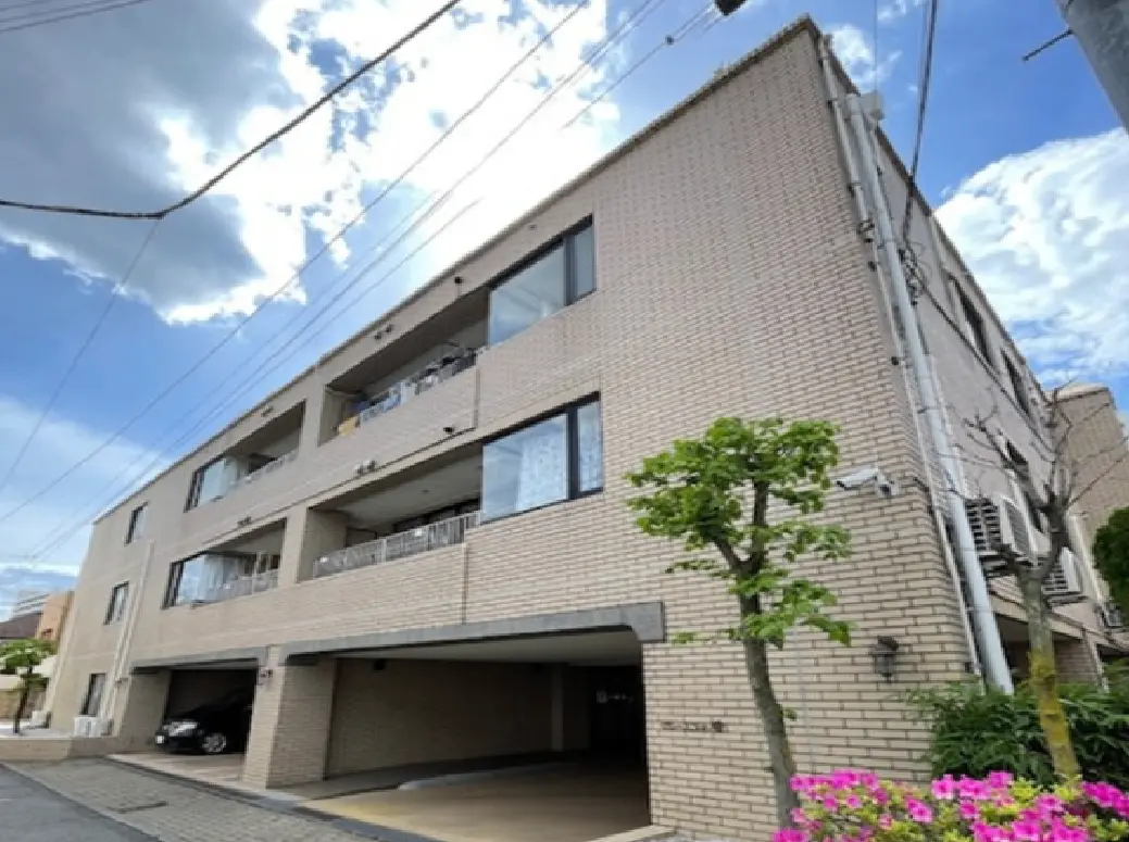 - 青空を背景にしたレンガ造りのアパート外観、ベランダと植栽が特徴の2階建ての住宅