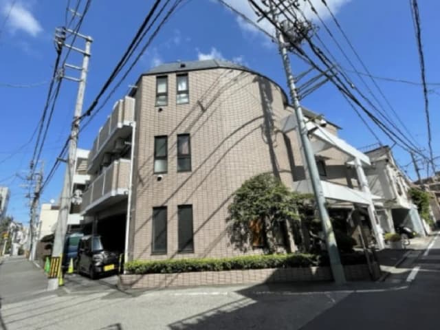 - 曲線的なデザインの外観を持つ住宅、青空と電線が広がる街角の風景