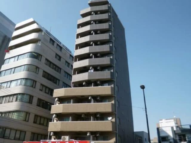 - モダンなビルの外観、隣接する建物と青空の背景、バルコニーが特徴の大きな住宅ビル