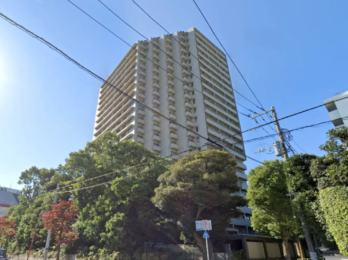 高層マンションの外観、周囲に緑豊かな木々、青い空と電柱のコンビネーション