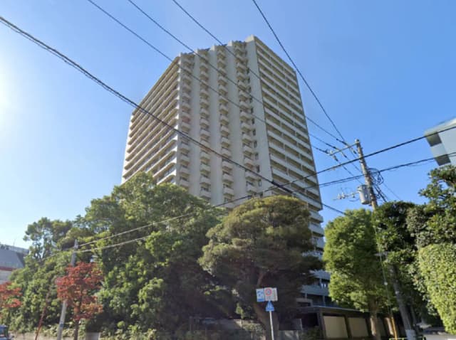高層マンションの外観、周囲に緑豊かな木々、青い空と電柱のコンビネーション