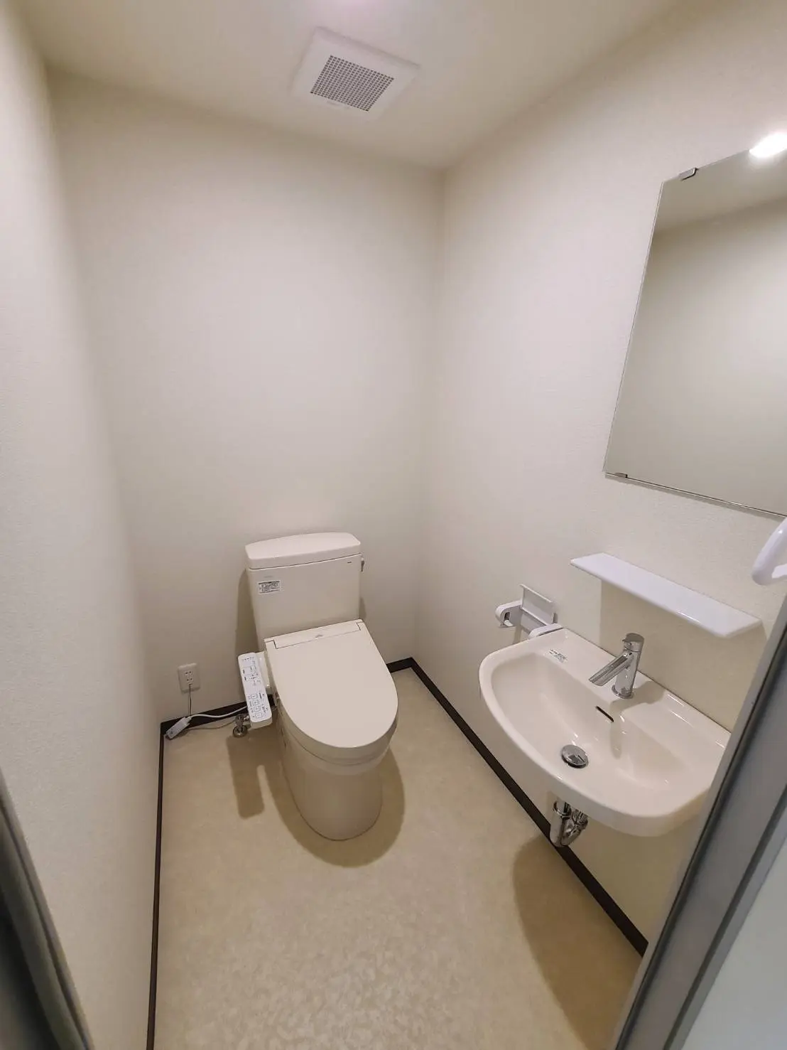 シンプルなデザインのトイレルーム、洗面台付き、壁掛けミラーと白い壁のインテリア