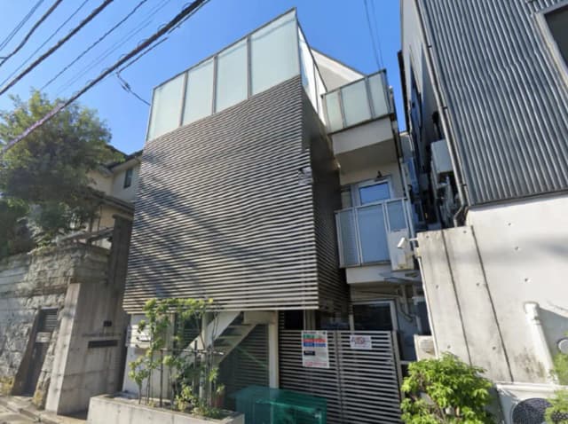 - 現代的なデザインの建物、ストライプ状の外壁とガラスパネルを持ち、周囲に植栽された緑豊かなエリア