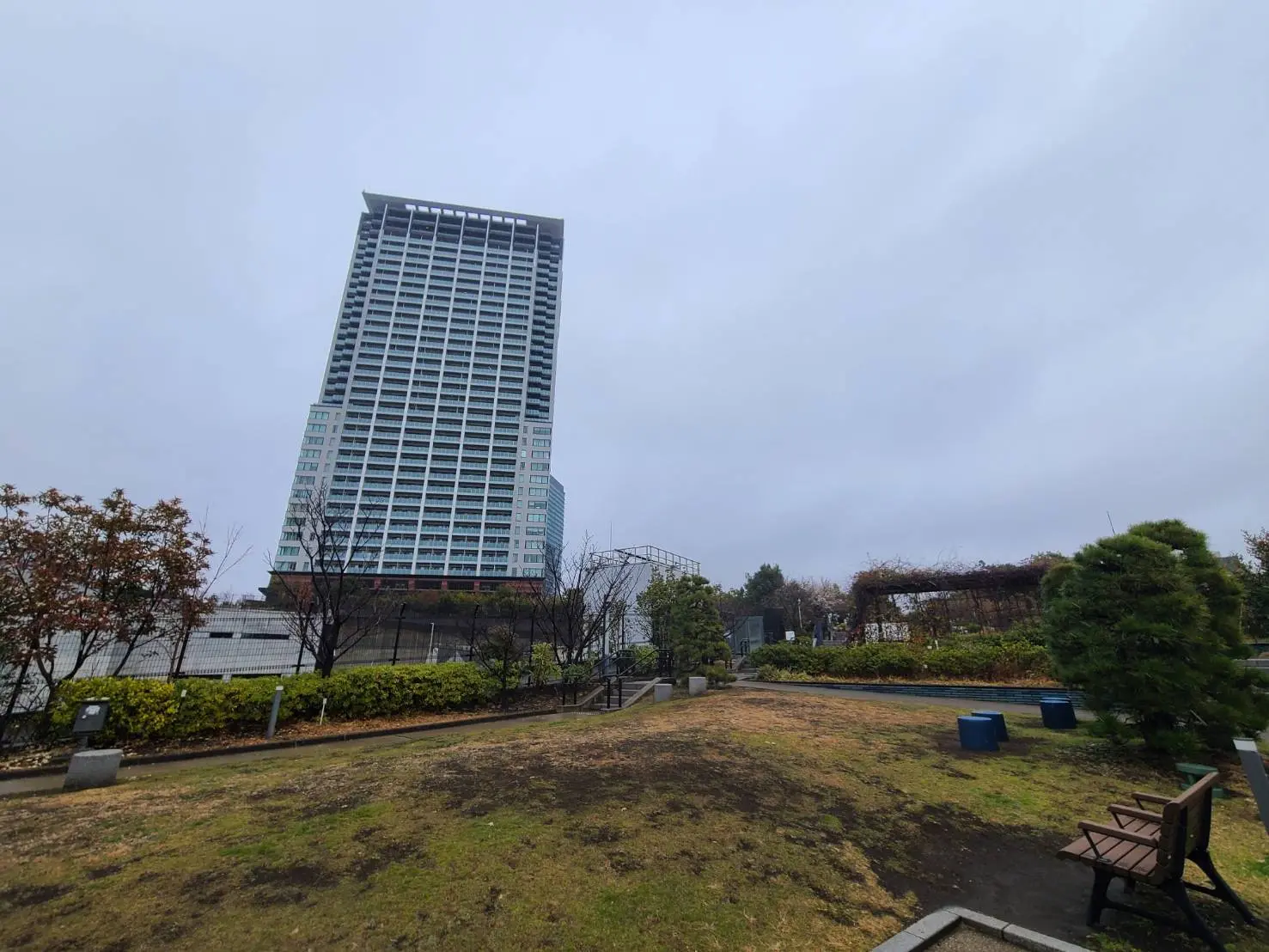 高層マンションの外観、公園のベンチと緑地から眺める都市景観