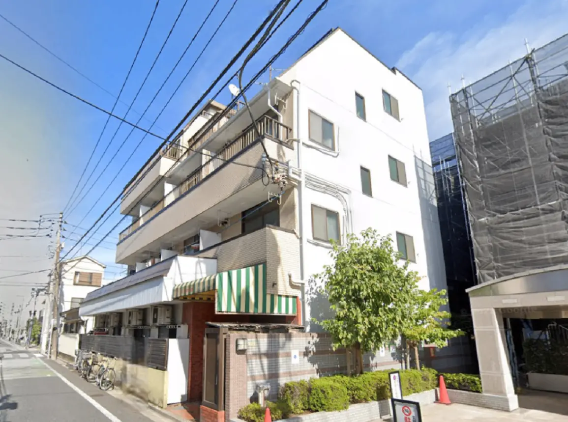 - 日当たりの良い白い外壁のマンション、クリーンなデザイン、周囲に自転車や緑の木々が見える街並み