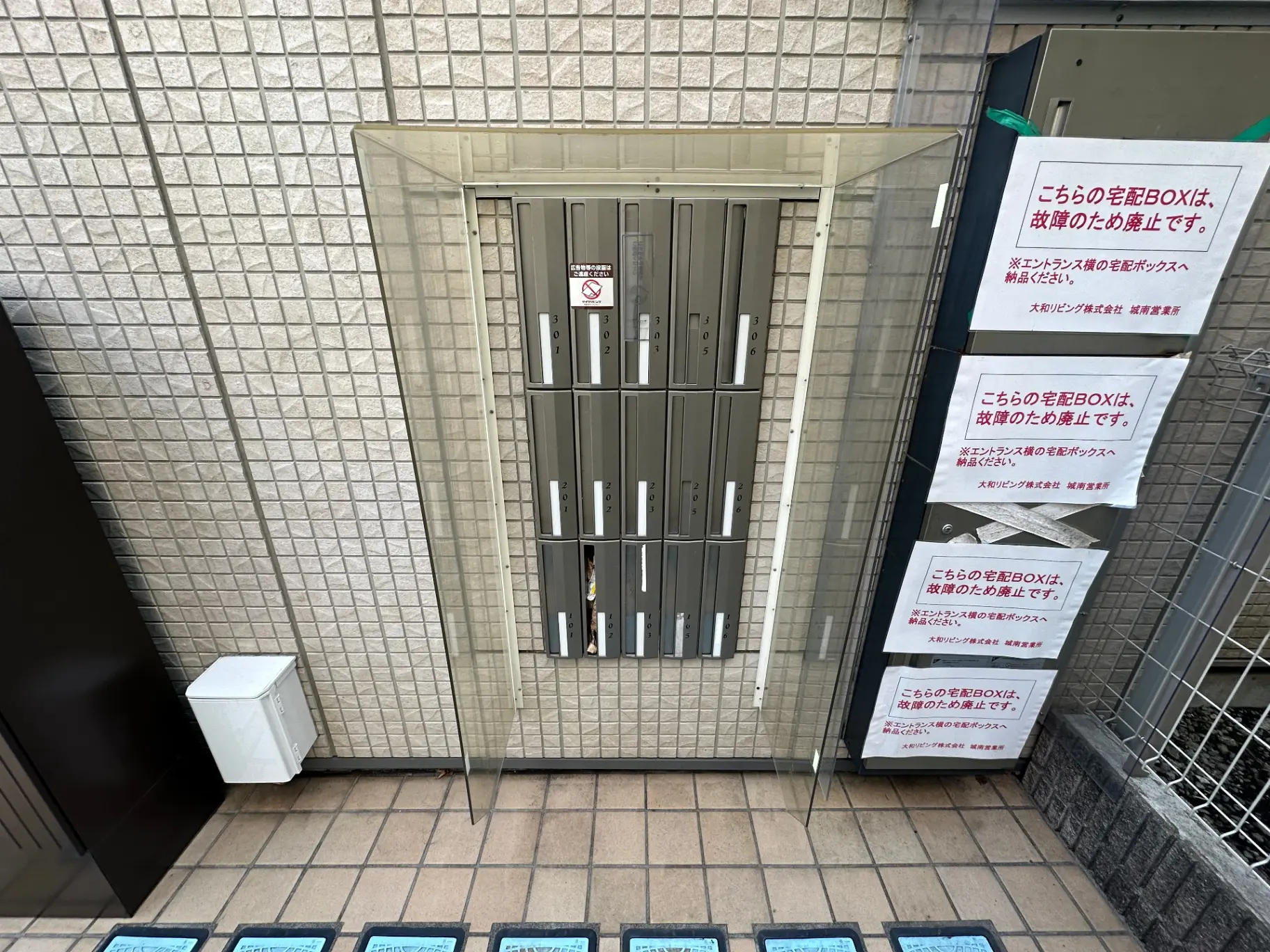 アパートの入り口にある郵便物受けBOX、禁煙の注意書き、宅配ボックスに貼られた連絡先案内のポスター