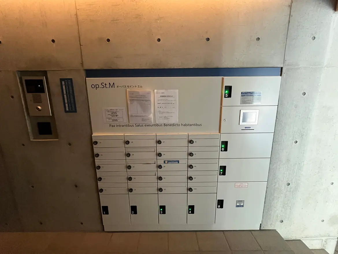 - 郊外のマンションエントランスに設置された宅配ボックスとインターホン、コンテンポラリーなコンクリート壁の背景