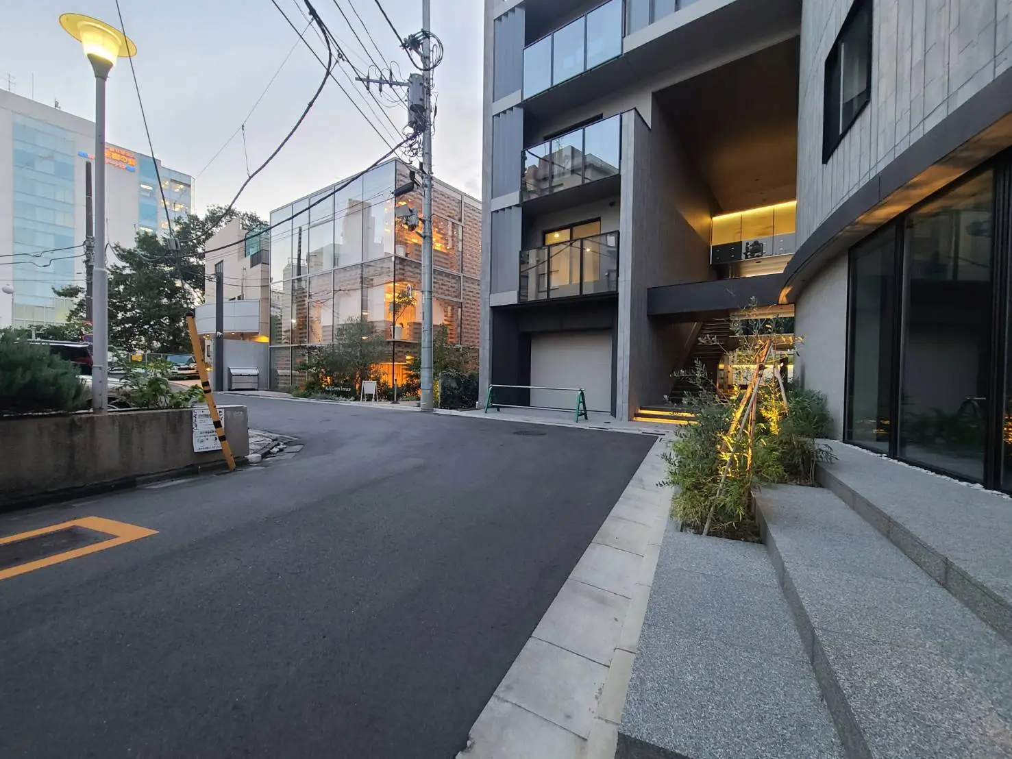 モダンな建築様式の都市型マンション、夜景を照らす街灯とイルミネーション、清潔感のある舗装された道路