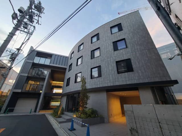 モダンでスタイリッシュな外観の都市型マンション、グレーの外壁と大きなガラス窓が特徴的な建築デザイン