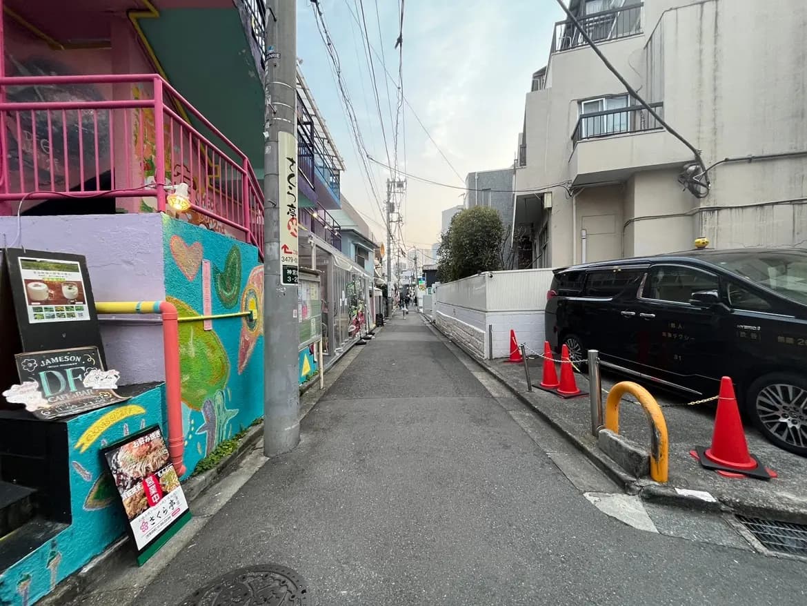 カラフルなグラフィティーアートが描かれた都市の路地、歩道と駐車スペースが見える景観