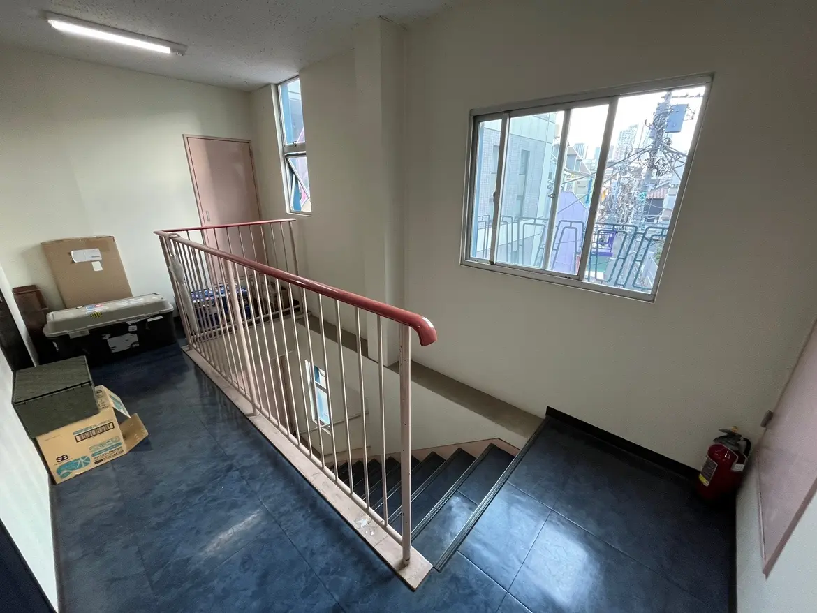 建物の内部にある階段と廊下、手すりが備わり日当たりの良い窓が見えるオフィス空間
