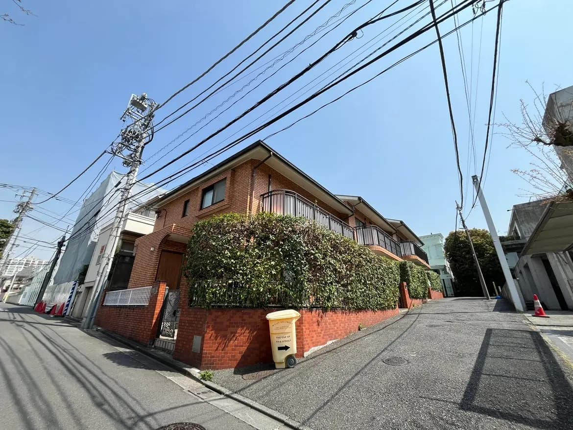 晴れた日の住宅街の通り、茶色のレンガ造りの家と多くの電線、青空