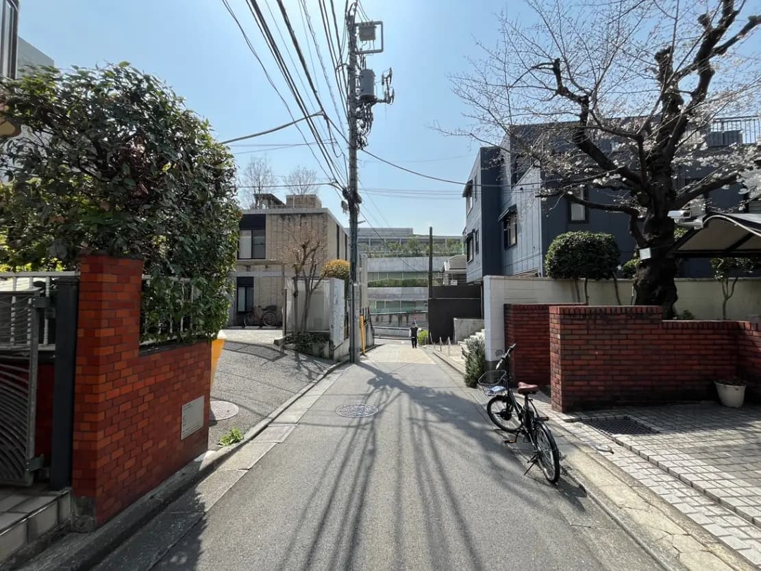晴れた日の静かな住宅街の風景、緑の植物とレンガの壁、自転車が置かれた歩道