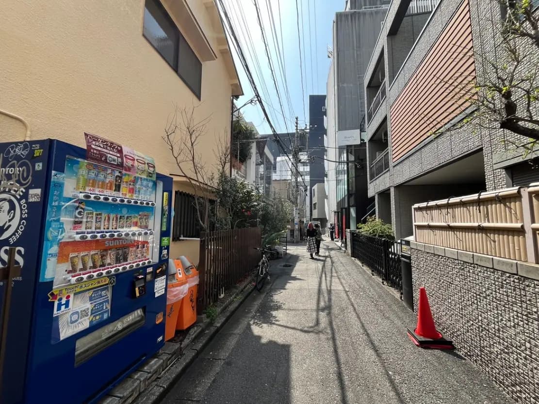 日本の都市の細い路地、自動販売機、自転車、歩行者、晴れた日の街並み