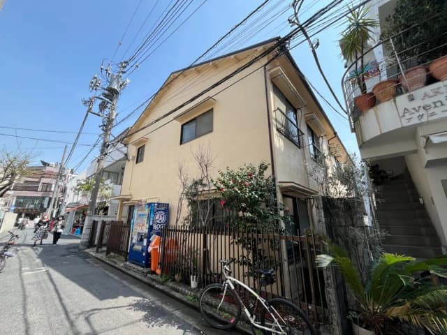 日本の住宅街の風景、昼間の晴れた日に撮影された二階建ての家と自転車、電信柱と多くの電線が見える
