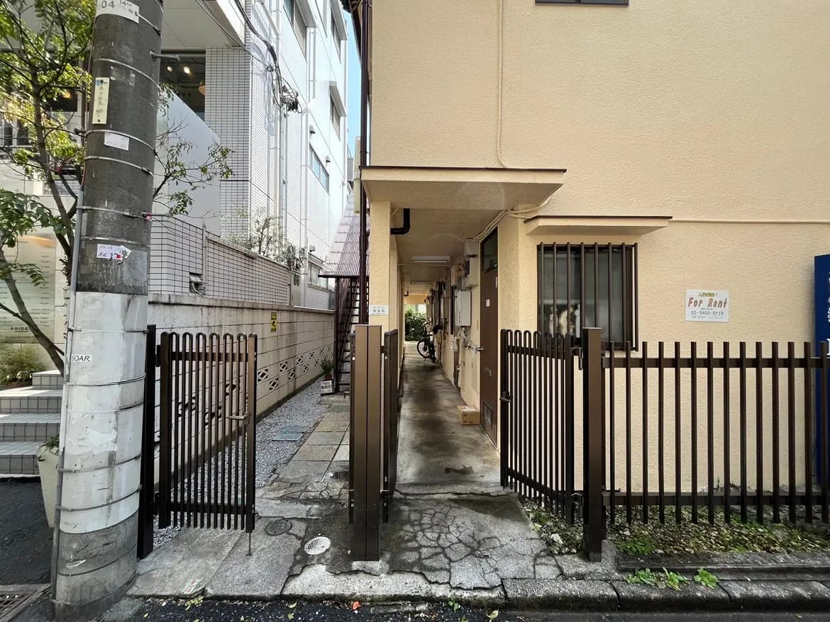 都市のアパートのエントランス、貸し出しの看板がある門、狭い通路