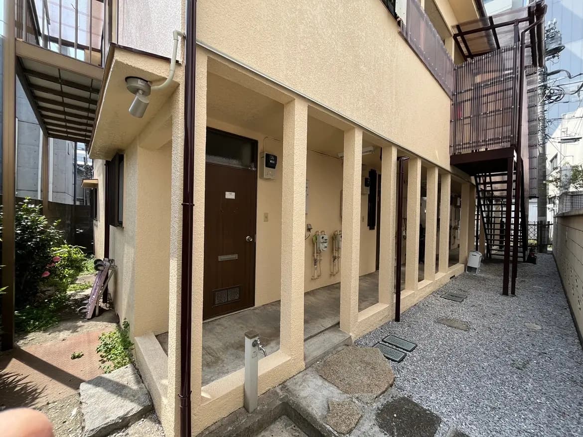 日本の住宅街にある一戸建ての玄関と外廊下、石畳のアプローチ、自然光が差し込む明るい外観