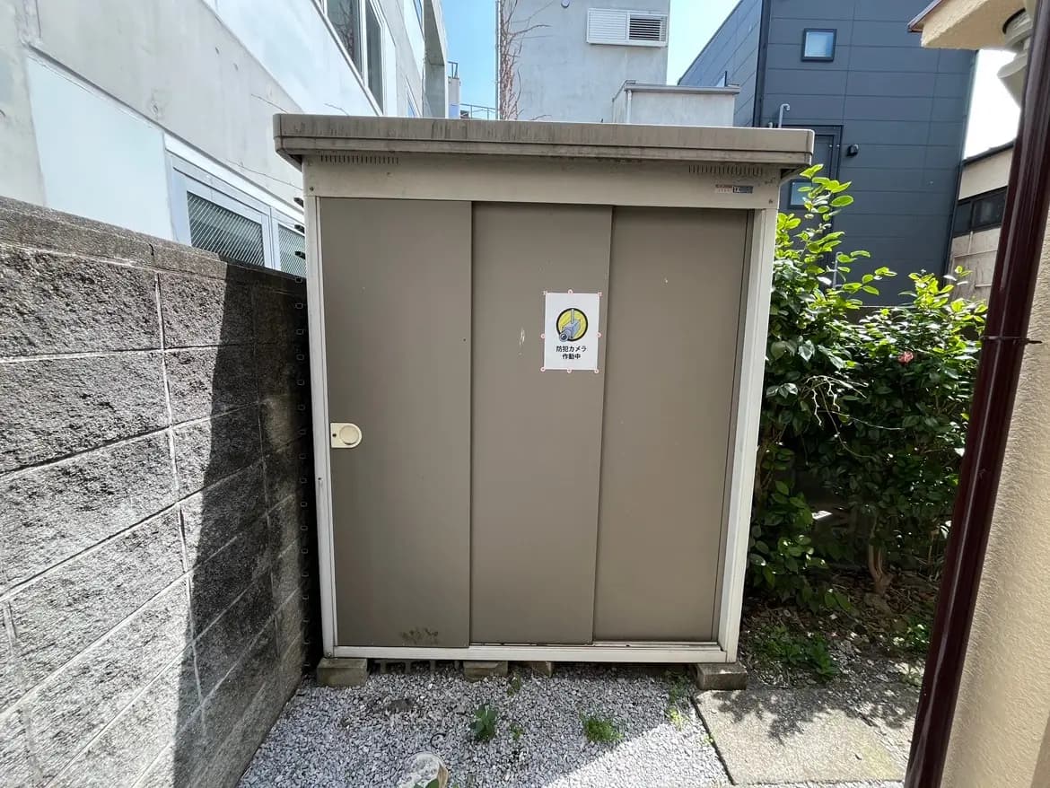 都市の中庭にある小さな灰色のドア、壁には警告の表示があるストレージスペース