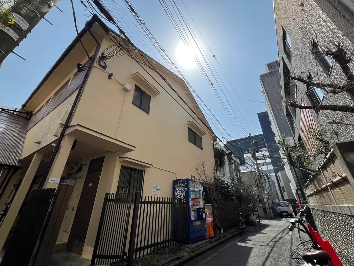 晴れた日の都会の路地、電線が交差する空、アパートとビルの間の狭い通り