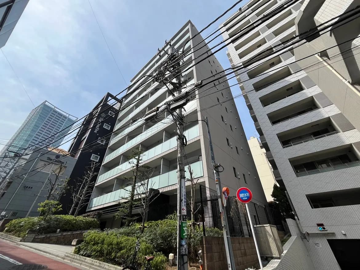 日本の都市の通りに面した現代的な建物群、晴れた日の青空、配電線が見える景観