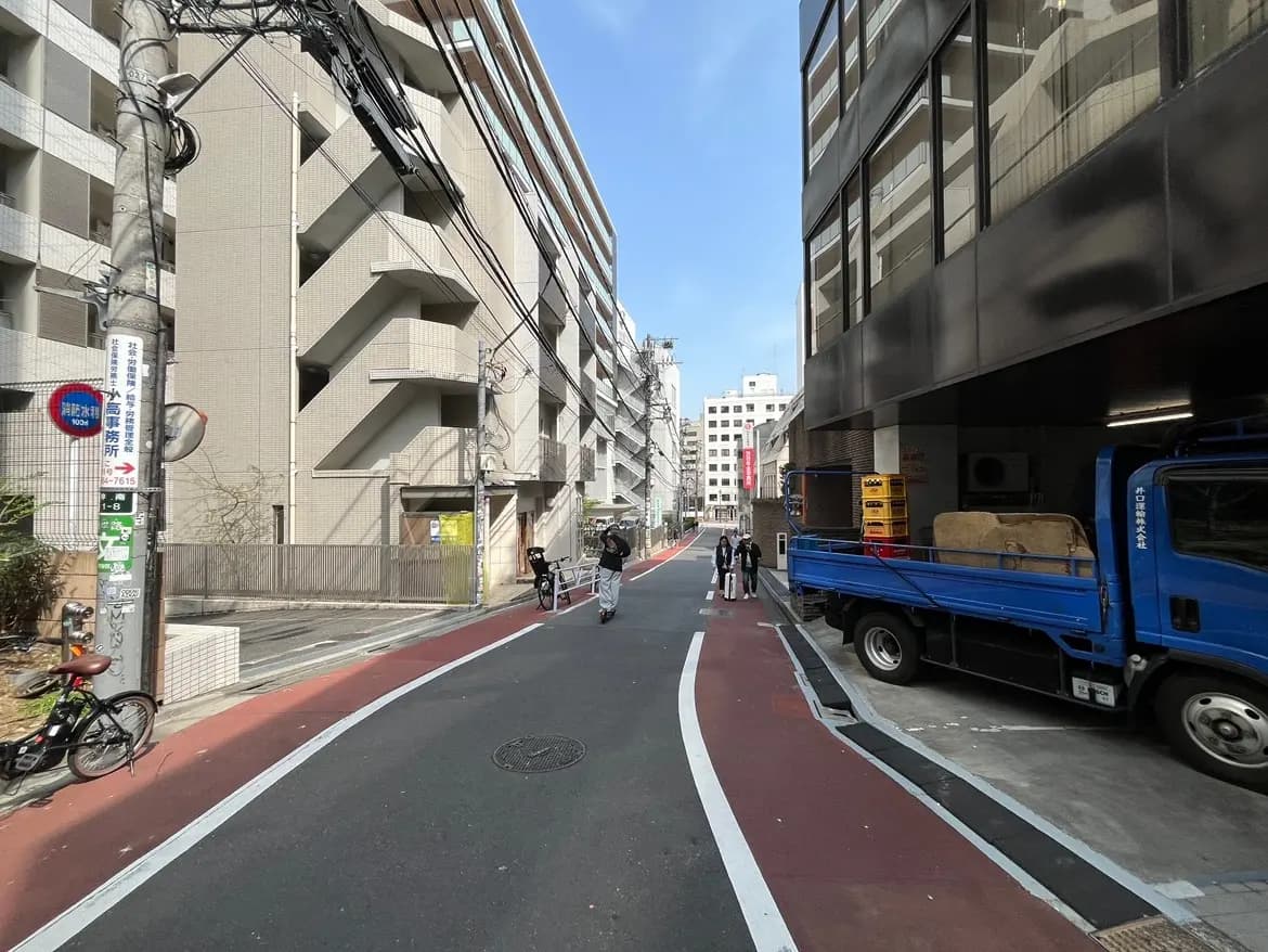日本の都市部の道路と歩行者、赤い自転車レーン、青いトラック、晴れた日の都市風景