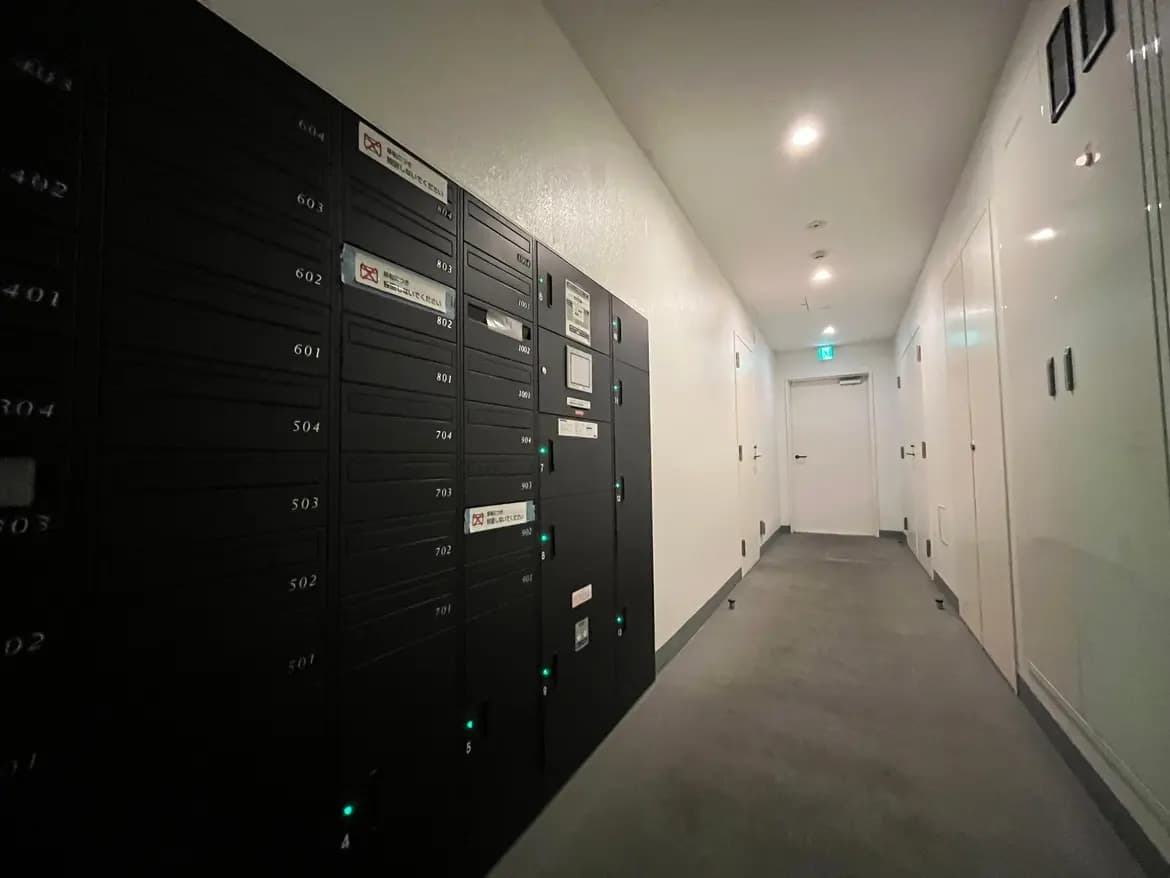 モダンなマンションの宅配ボックス付きエントランスホール、清潔感のある廊下、照明が施された快適な共用部分