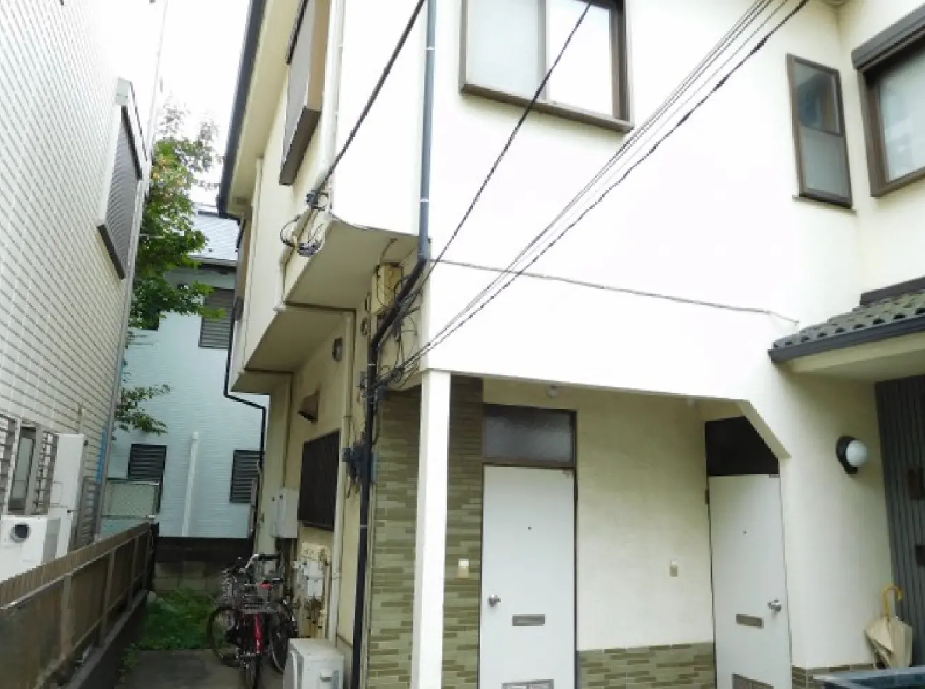 - 住宅街に立地する二階建ての建物、隣接する家との距離が近く、外観には白壁が使用されている様子