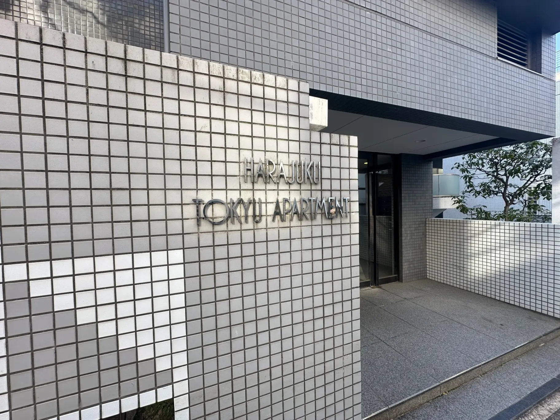 原宿TOKYUアパートメントのエントランス、タイルの壁にアパート名が刻まれたデザイン