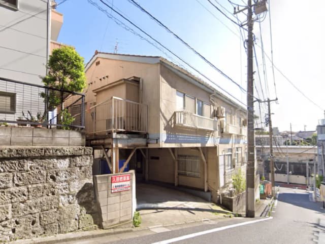 - 複数の住宅が立ち並ぶ街並み、道路や電柱がある風景、アプローチのある家と立て看板が見える景観