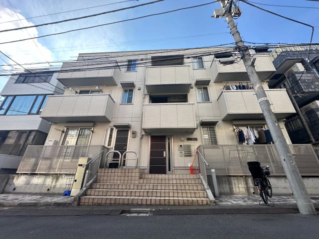 日本の郊外のモダンなアパートの外観、白い壁に囲まれたバルコニー付き、洗濯物が干されている