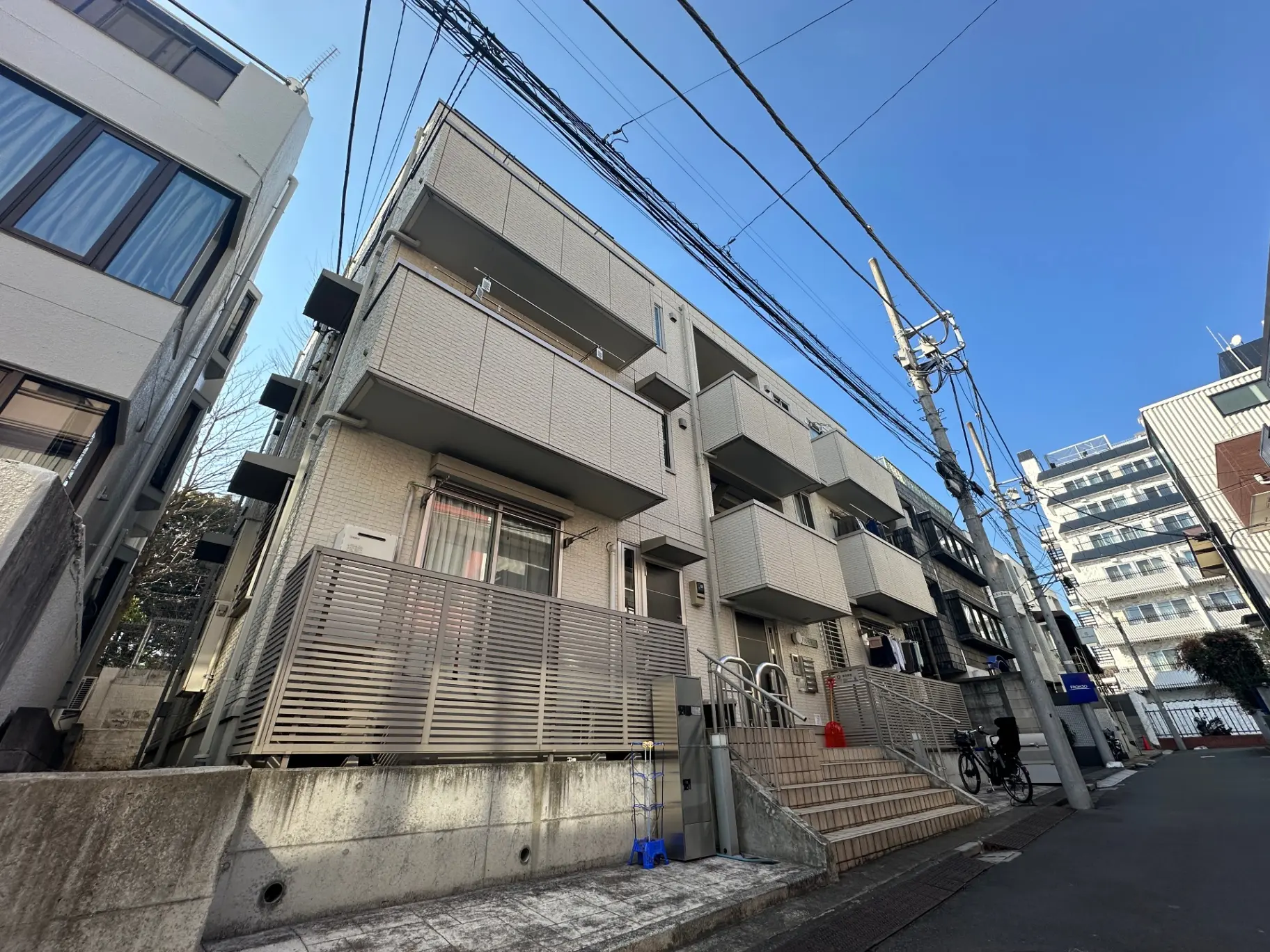 都市のアパートメントビル、電柱と配線が見える青空の下の住宅街