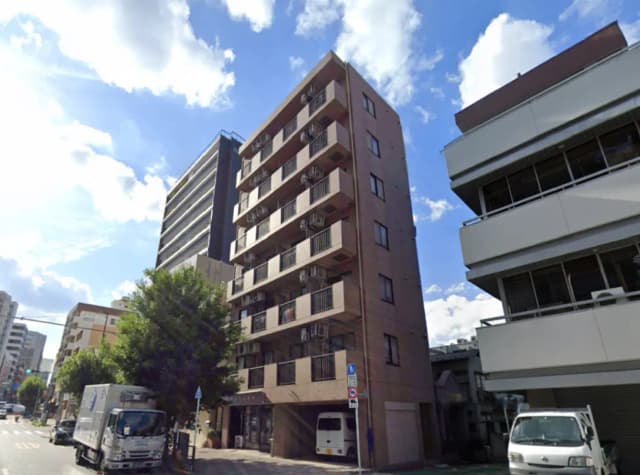 - 都市に立つ6階建てのレンガ造りのアパートメントビル、バルコニーが並ぶ外観と青空が広がる風景