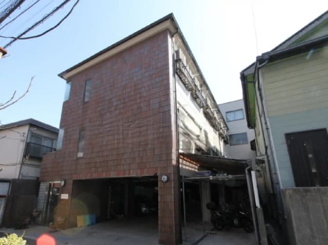 - モダンな外観の三階建て住宅、タイル貼りのファサードと駐車スペース、周囲の建物と青空のコントラスト