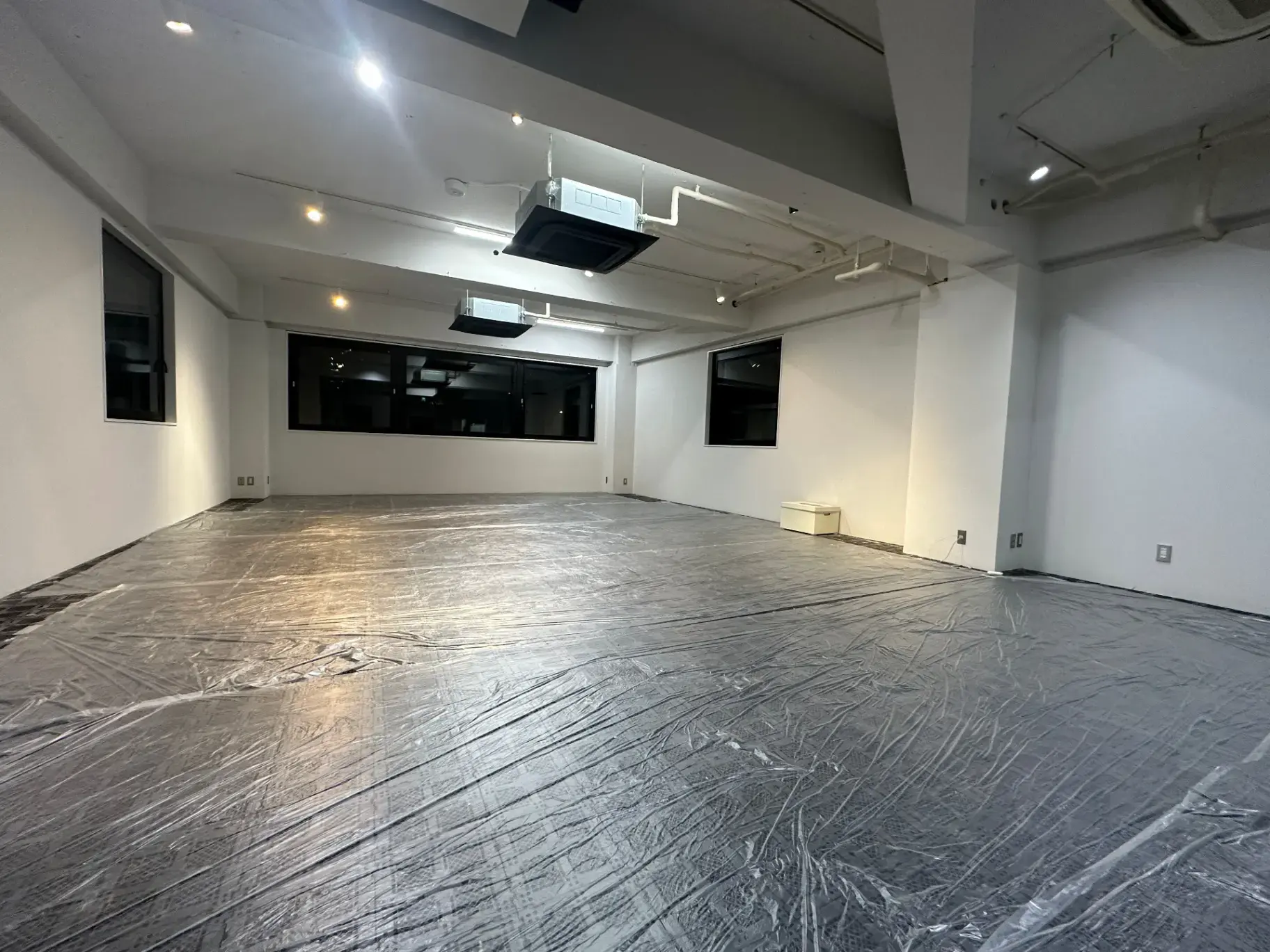 広々とした空間にプロジェクター設置可能な天井、明るい照明のオフィス空間
