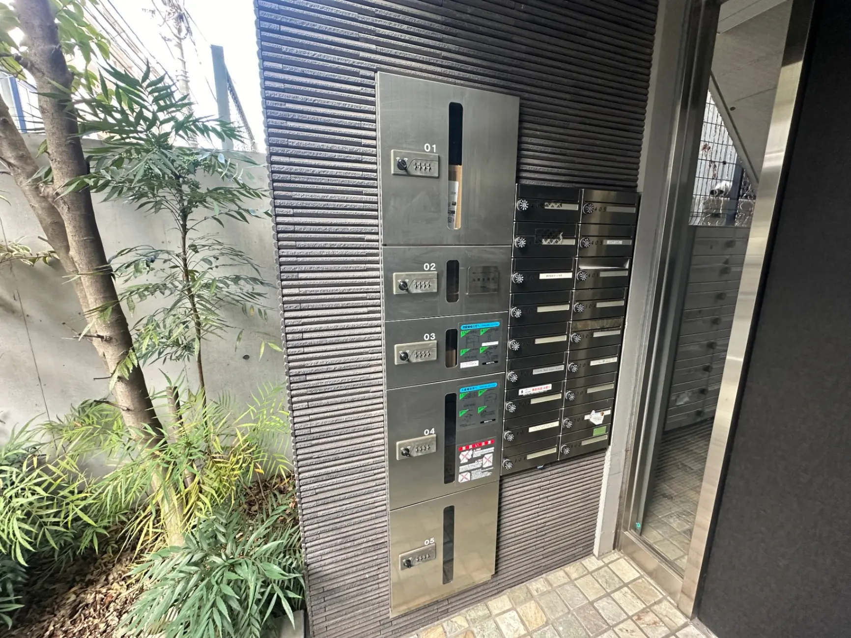 日本のマンションのエントランスと郵便受け、植栽と石畳のあるエクステリアデザイン