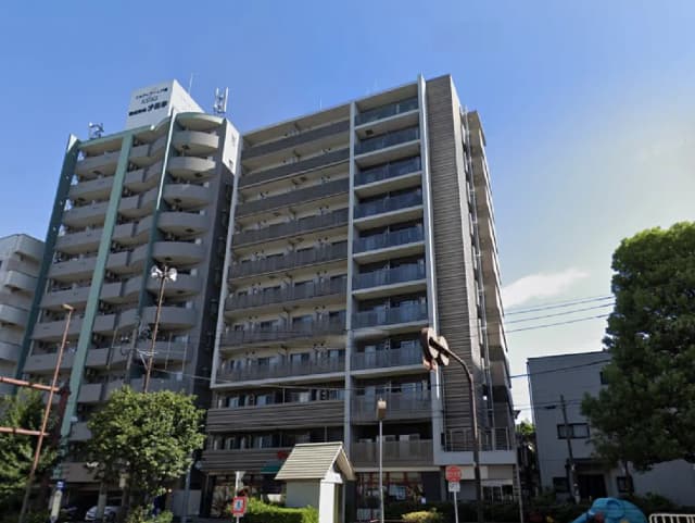 - モダンなデザインの集合住宅、バルコニーが特徴的で青空を背景にした外観、周囲には豊かな緑が広がる景観