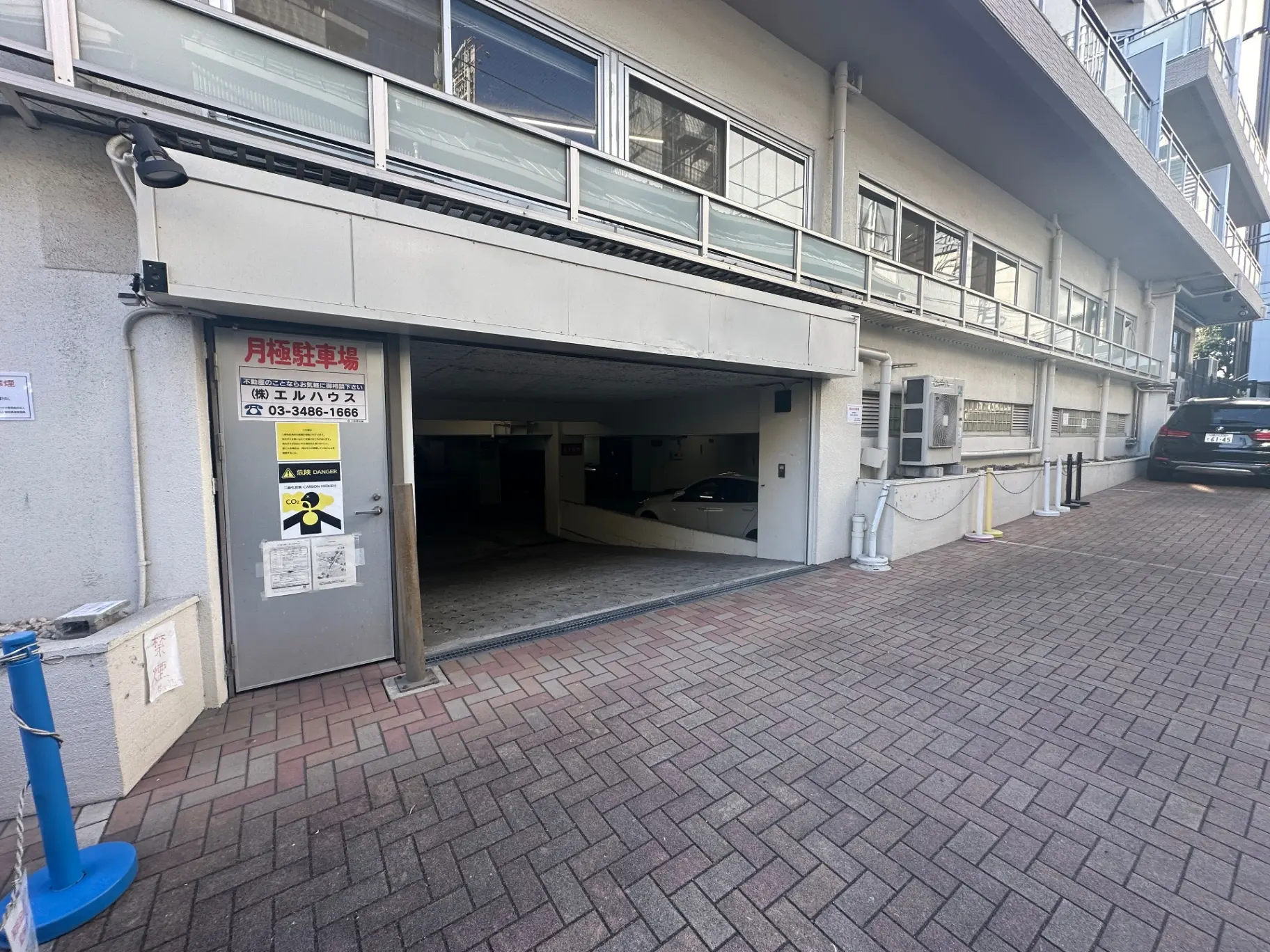 都会の住宅街にある開放的なコインパーキングの入り口、キャッシュレス対応の自動精算機付き