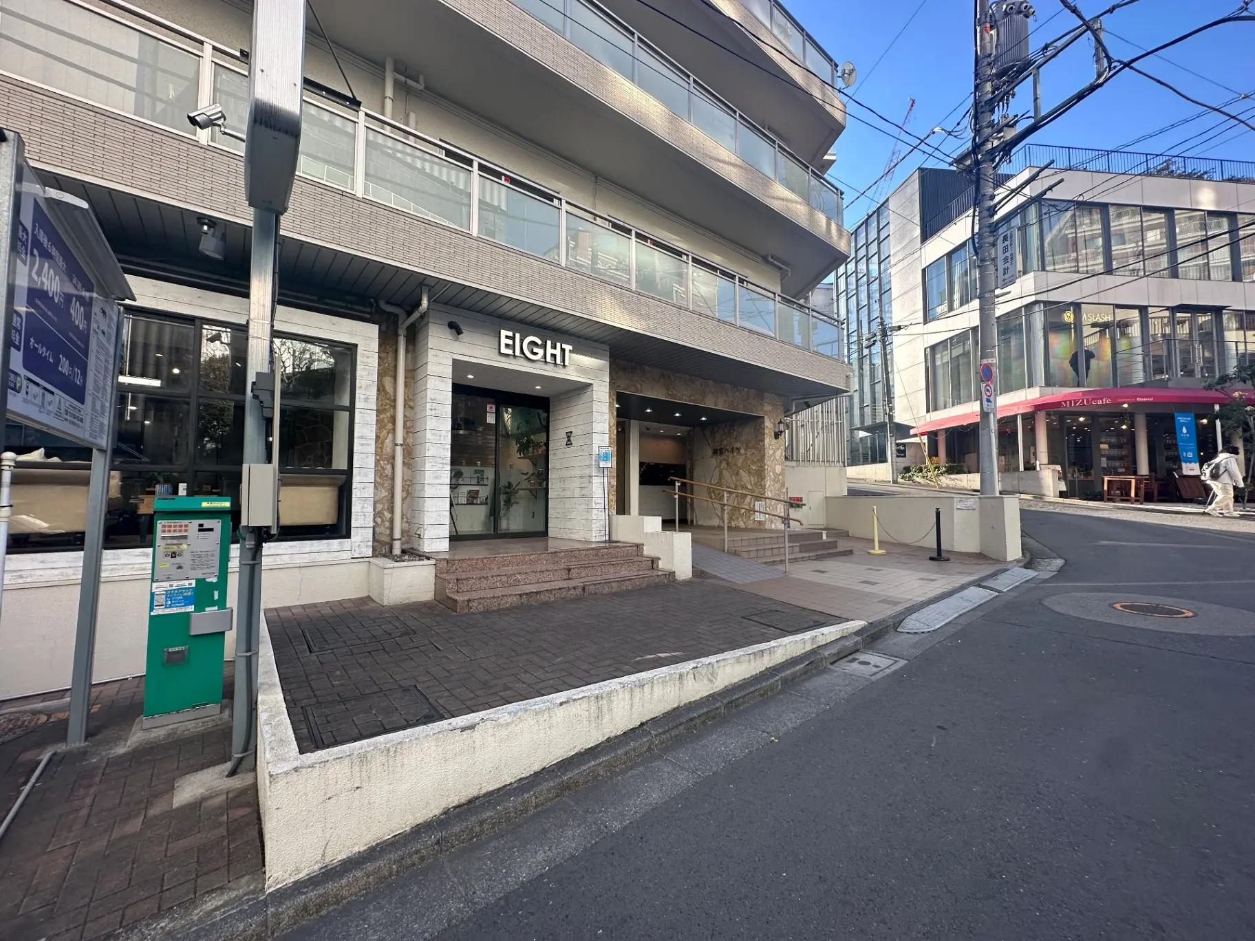 ビルの1階にある「EIGHT」という看板の店舗、石造りの壁とアクセスしやすいエントランス、周囲にカフェや他のビジネスがある都市風景