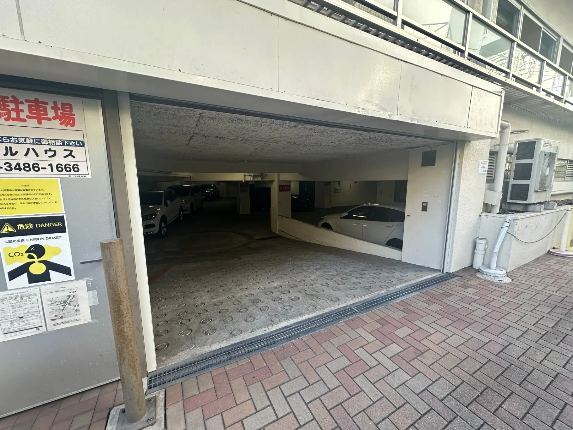 建物の地下駐車場の入口、セキュリティ警告看板が掲示されている都市のアパートメント