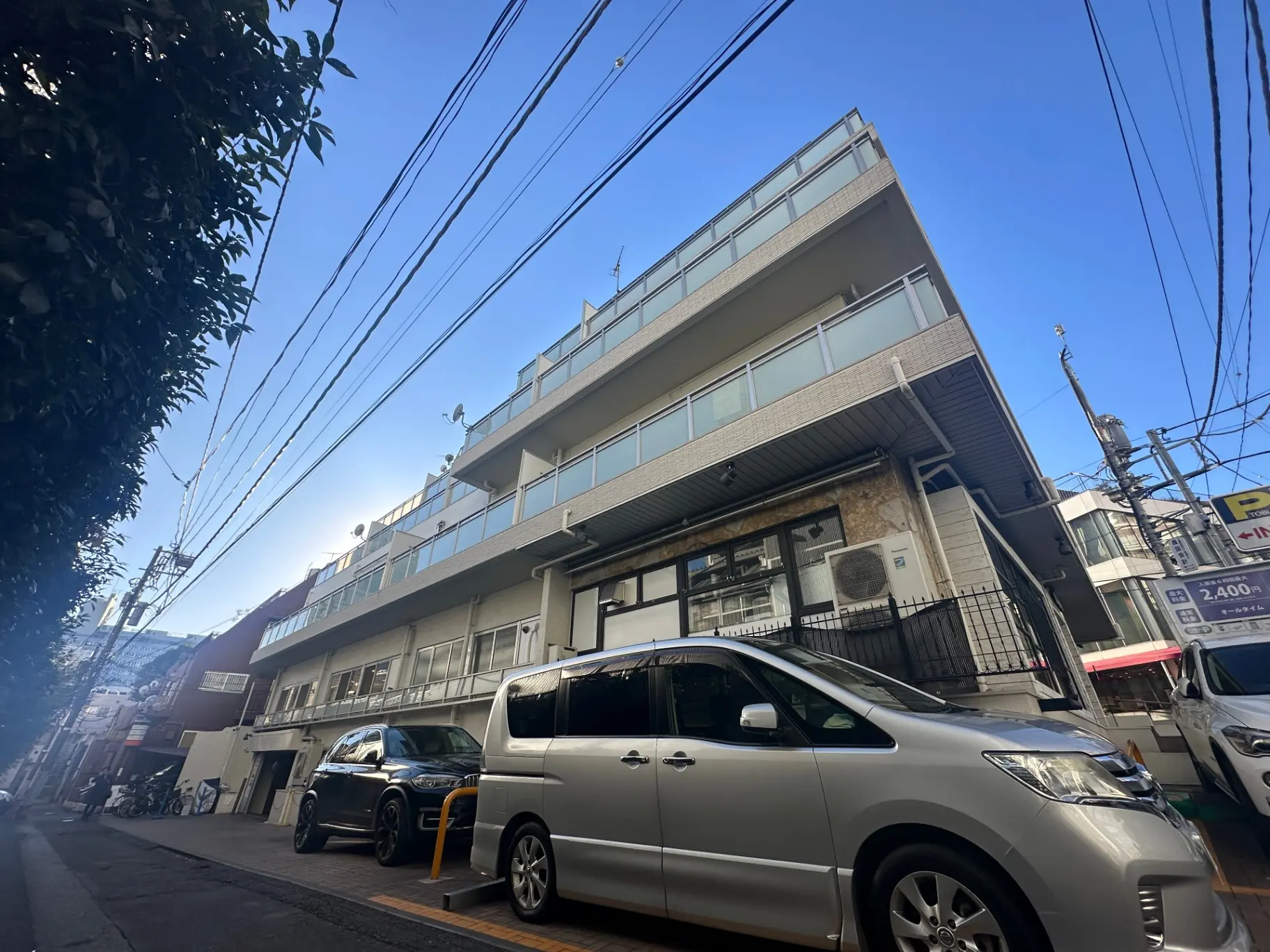 都市風景の日本の住宅とアパート、青空と通り沿いの駐車場付き