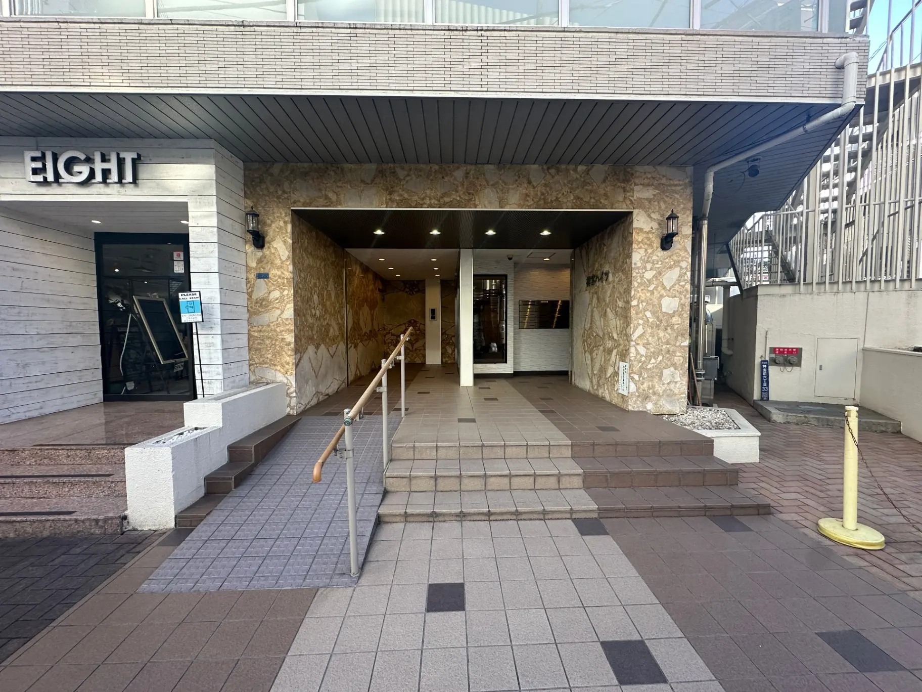 エイトと書かれた建物の入り口、石材と木材で装飾された外観、手すり付きの階段