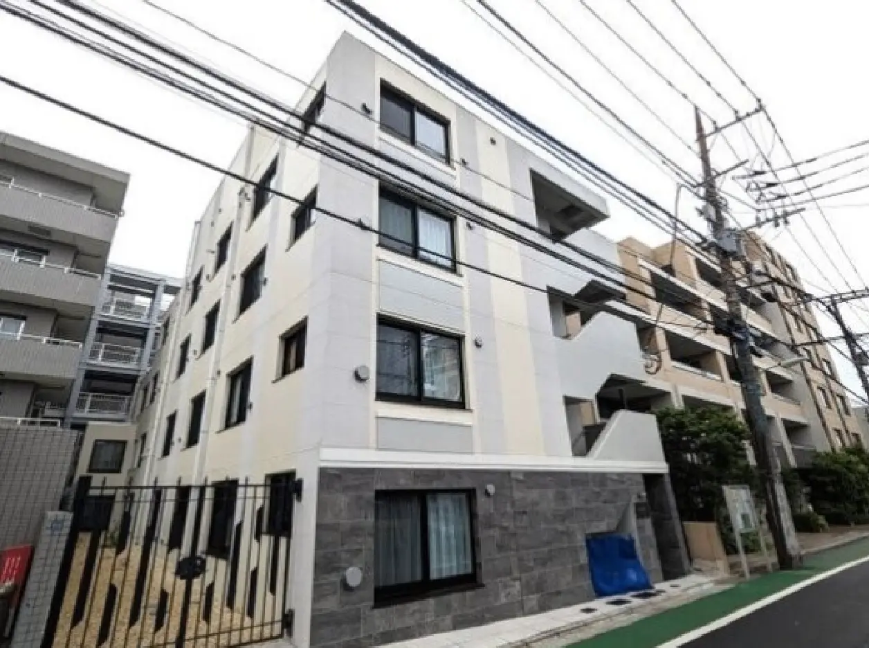 - 現代的なデザインのアパートメントビル、清潔感のある外観と白色の外壁、隣接する建物と電柱のある都市の風景