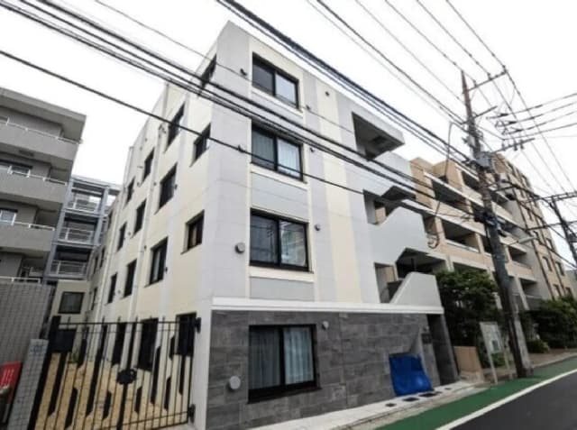 - 現代的なデザインのアパートメントビル、清潔感のある外観と白色の外壁、隣接する建物と電柱のある都市の風景