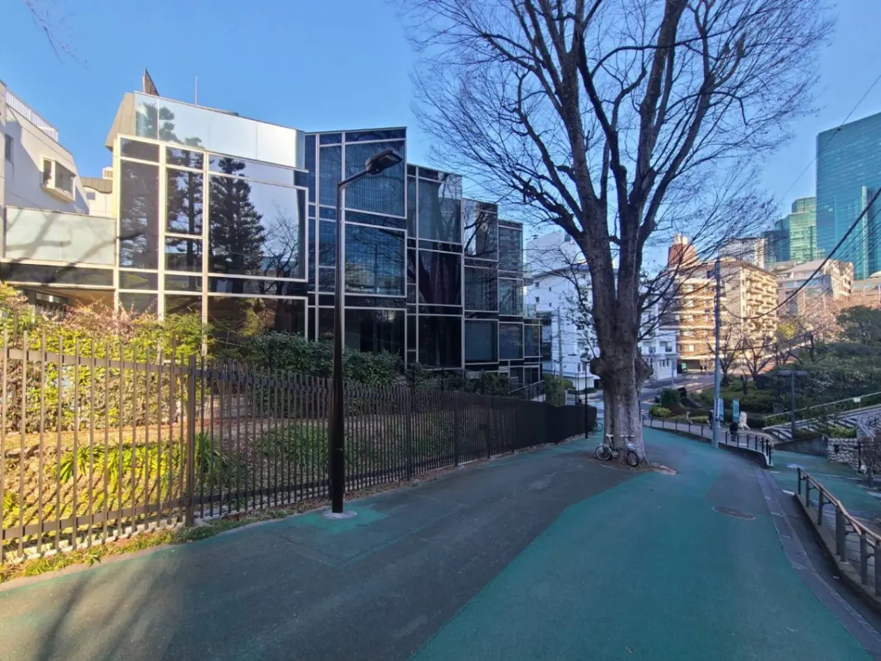 都会の景観を持つモダンな建築物と緑豊かな公園、背景に高層ビルと青空
