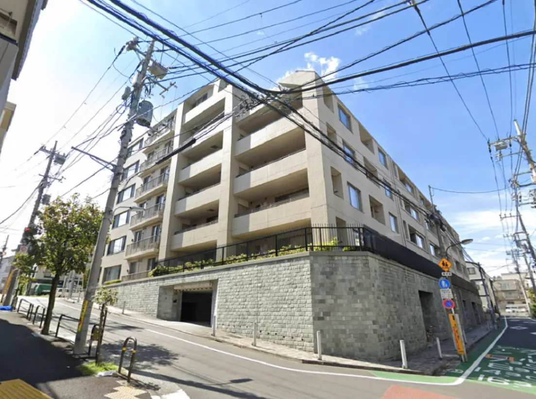 - 外観が見えるマンション、周囲には電柱や電線があり、緑豊かな植栽が施されたテラスと道路の近くの景観
